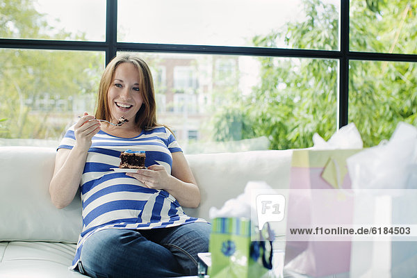Geburtsfest Baby Shower Babyparty Europäer Frau Couch Schwangerschaft essen essend isst