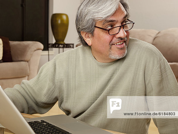 Hispanic man using laptop in living room