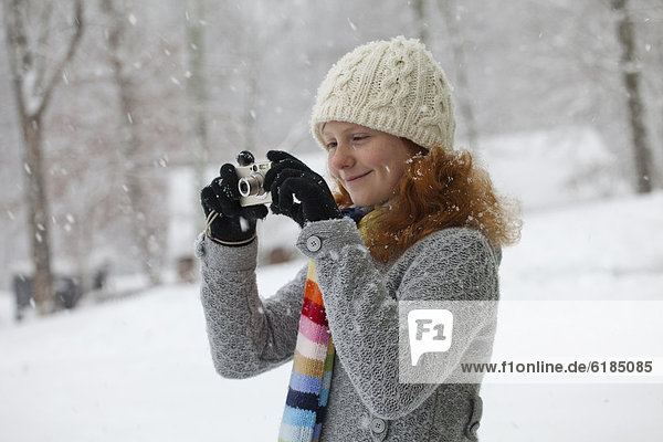 Caucasian girl taking photographs in snow