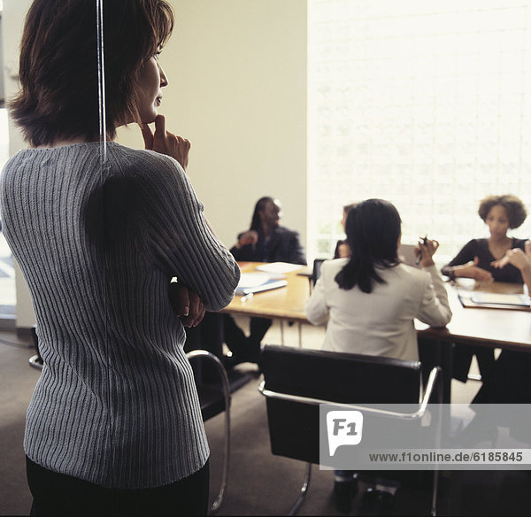 Businesswoman watching co-workers in conference room