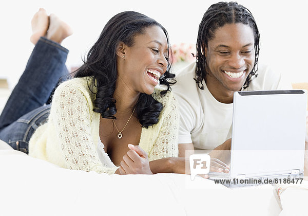 African couple on laptop in bed