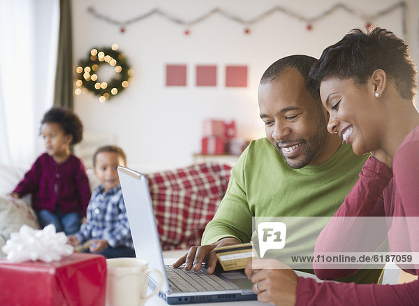 Black mother and father shopping online with credit card
