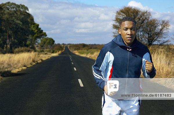 Mixed race man running on remote road