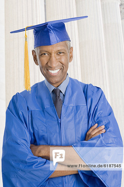 Mixed race man in graduation cap and gown