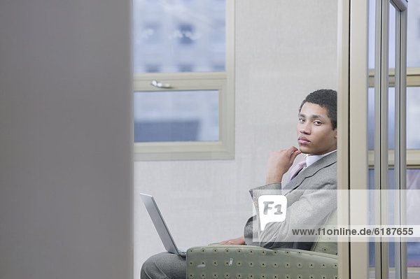 Mixed race businessman working on laptop and looking serious