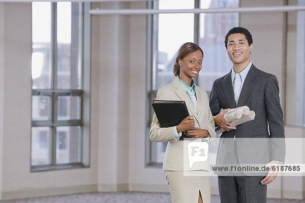 Multi-ethnic business people holding blueprints and binder
