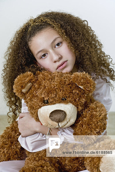 Mixed race girl in nightgown with teddy bear