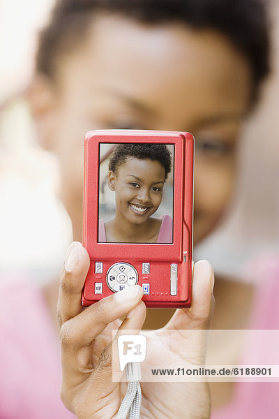African woman taking self-portrait with digital camera