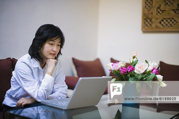 Asian woman using laptop in livingroom