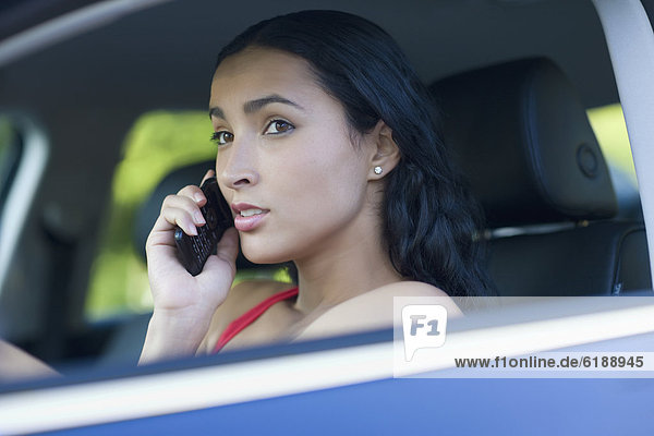 Hispanic woman talking on cell phone while driving