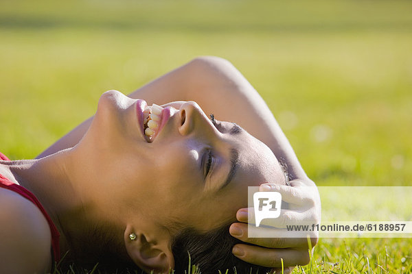 Hispanic woman laying in grass smiling