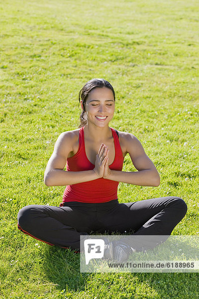 Hispanic woman practicing yoga in grass
