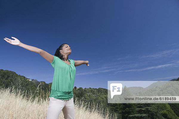 Mixed race woman outdoors with arms outstretched