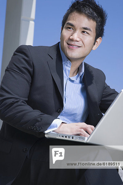 Asian businessman working on laptop outdoors