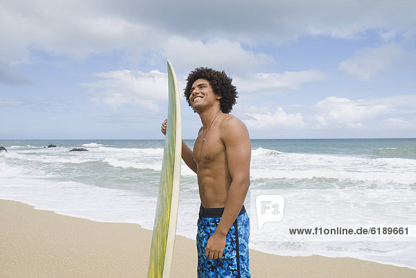 African man at beach with surfboard