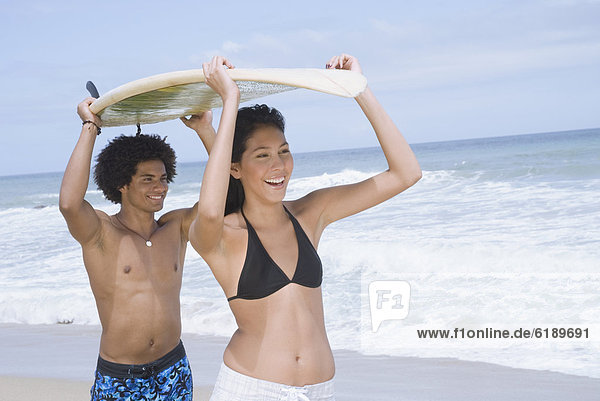 Couple carrying surfboard at beach