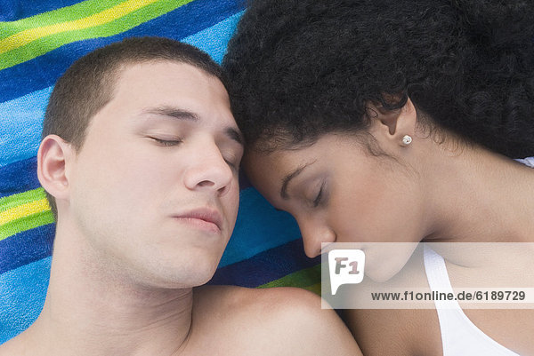 Multi-ethnic couple sleeping at beach