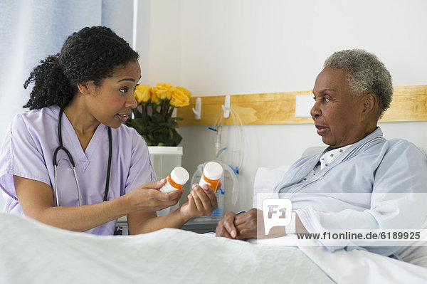 Nurse explaining medication to patient in hospital bed
