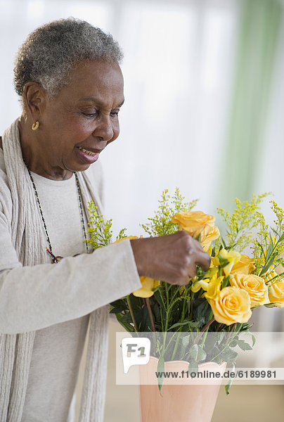 Black woman arranging roses in vase