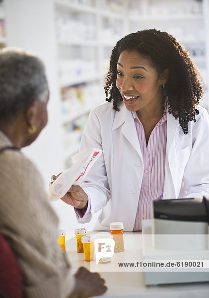 Pharmacist handing medication to woman