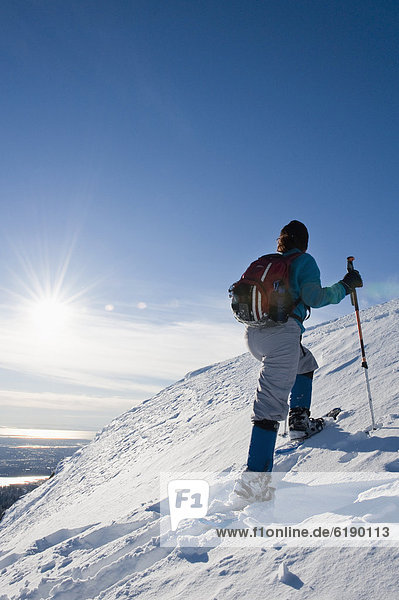 Hispanic woman snowshoeing up hill