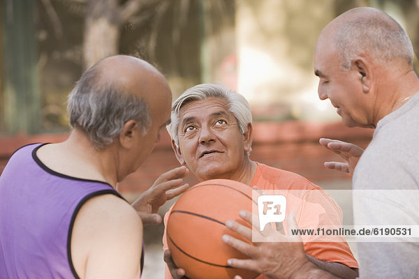 Senior Chilean men playing basketball together