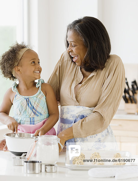 African grandmother baking cookies with granddaughter