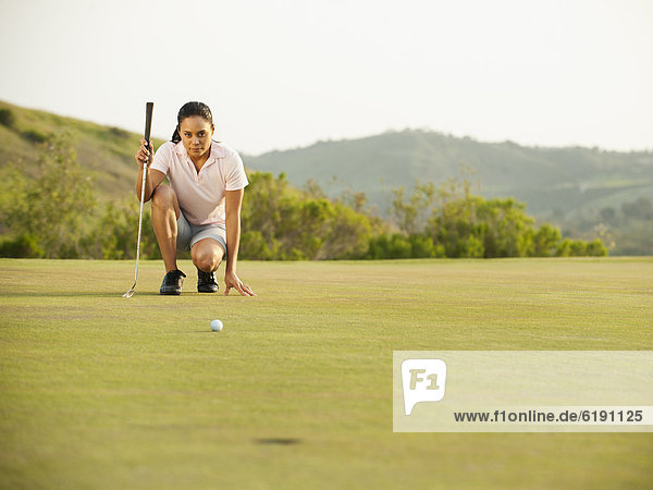 Mixed race woman checking ground on golf course