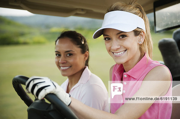 Women driving golf cart on golf course