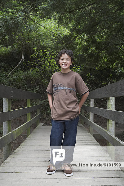 Mixed race boy crossing wooden bridge