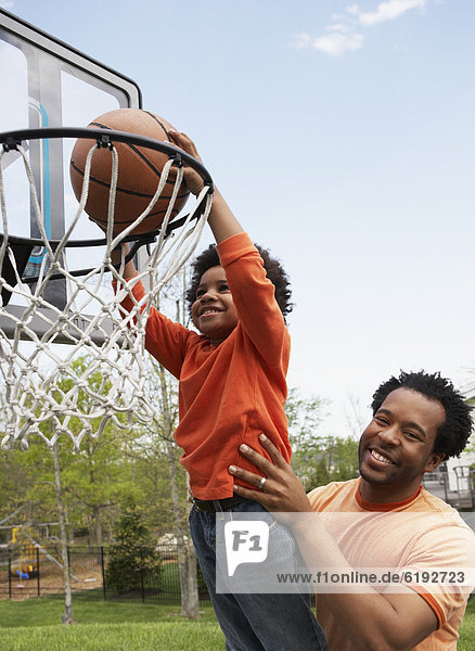 Menschlicher Vater  Sohn  heben  Basketball  einlochen