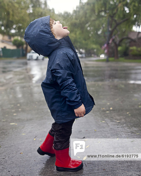 Caucasian boy catching raindrops on tongue