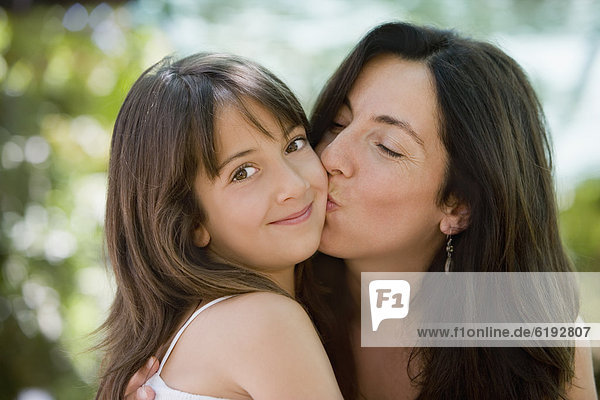 Hispanic mother kissing daughter
