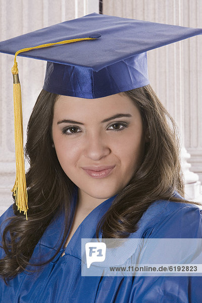 Hispanic teenage girl in graduation cap and gown