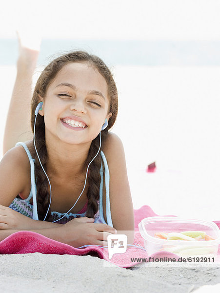 Hispanic girl listening to mp3 player on beach