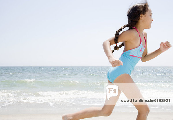 Hispanic girl running on beach