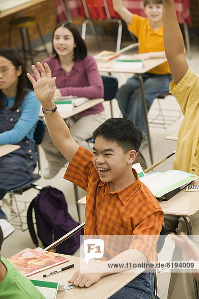 Asian student raising hand in classroom