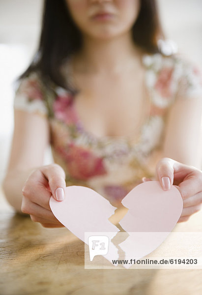 Korean woman holding torn paper heart