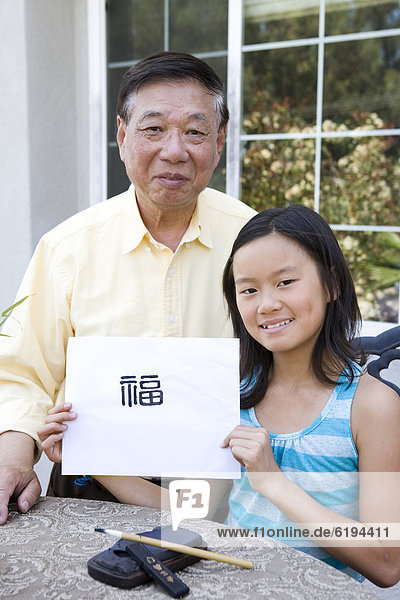 Chinese grandfather teaching granddaughter calligraphy
