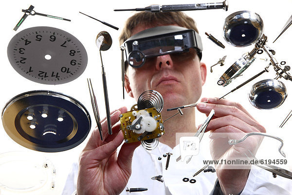 Feinmechaniker  Uhrmacher  bei der Reparatur eines Uhrwerks  Weckers  mit Lupenbrille