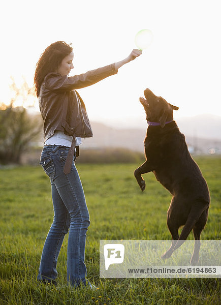 Caucasian woman playing with dog in field