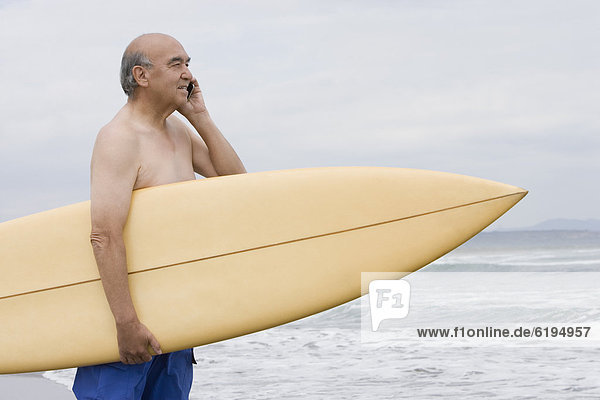 Handy Senior Senioren Mann sprechen Strand Hispanier halten Surfboard