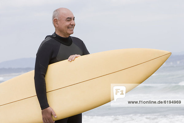 Senior Senioren Mann Strand Hispanier halten Surfboard