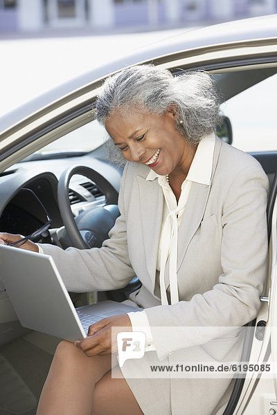 African businesswoman using laptop in car