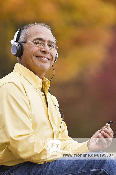 Hispanic man wearing headphones holding mp3 player