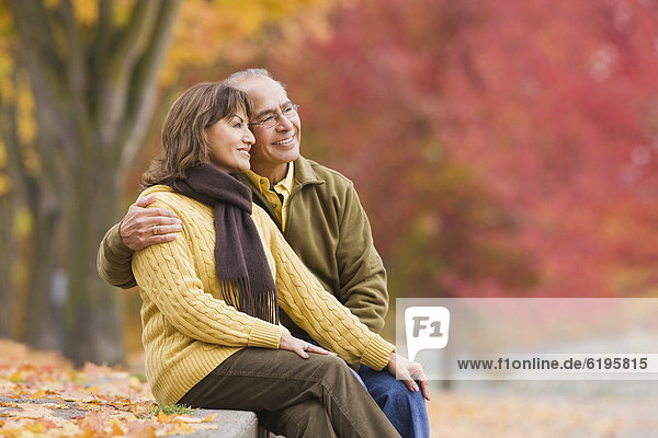Hispanic couple sitting outdoors in autumn