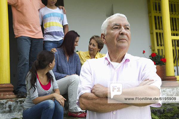 Stern Hispanic man with family in background