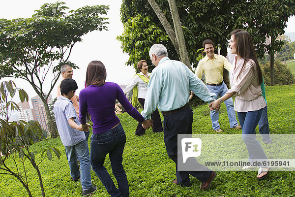 Hispanic family holding hands in a circle outdoors