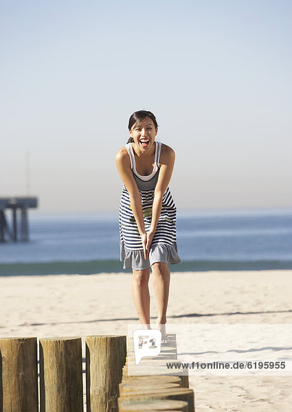 Asian woman standing on posts at beach