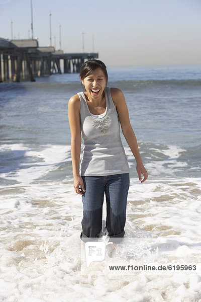 Asian woman wading near pier at beach